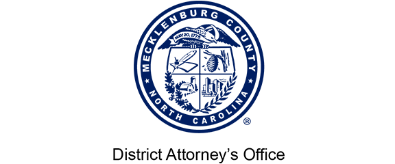 Seal of Mecklenburg County, North Carolina, with four quadrants and official symbols. Text below reads “District Attorney’s Office.”.