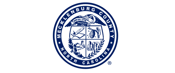 Seal of Mecklenburg County, North Carolina, featuring symbols such as a quill, beehive, horn, and buildings, bordered by text stating the county and state name.